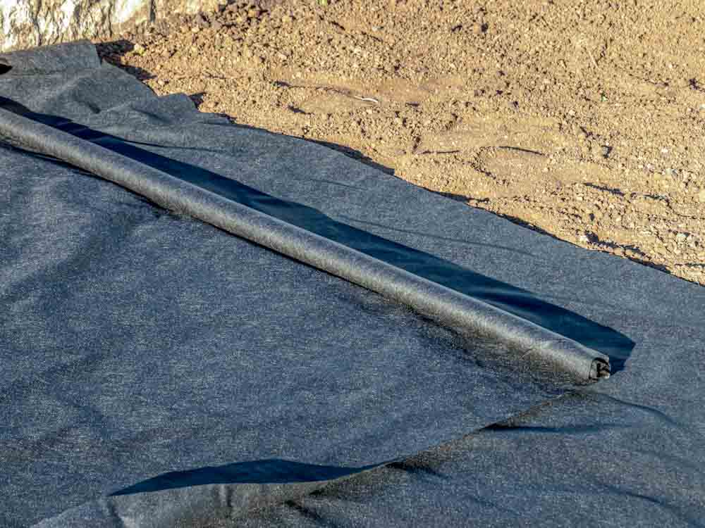 Unrolling filter fabric on compacted base